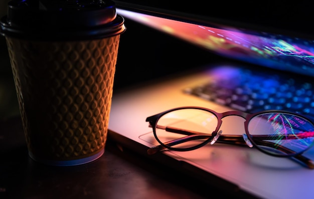 15 website Speed Optimization Tips for Improving site Speed in 2023 Free photo a laptop half closed in the dark with colourful glow cup of coffee and glasses